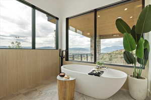 Bathroom featuring a mountain view, wood walls, a freestanding bath, and marble tiled flooring
