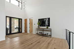 Entryway featuring wood finished floors, a chandelier, a high ceiling, and french doors