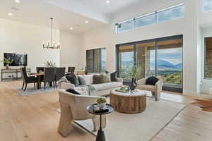 Living area featuring a chandelier, light wood-style floors, recessed lighting, a towering ceiling, and a mountain view