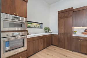 Kitchen featuring light wood finished floors, stainless steel double oven, and light countertops