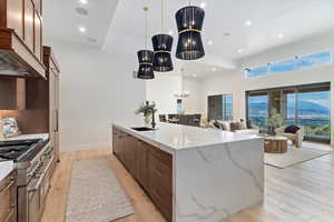 Kitchen featuring a chandelier, a mountain view, a large island with sink, light wood finished floors, and a towering ceiling