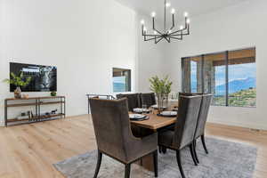 Dining room with a towering ceiling, light wood finished floors, a chandelier, and a mountain view