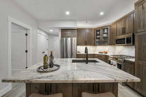 Kitchen featuring tasteful backsplash, a breakfast bar area, recessed lighting, stainless steel appliances, and light wood finished floors