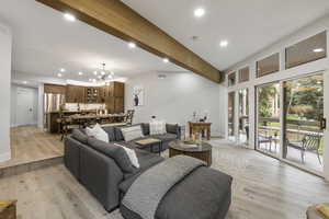 Living room with recessed lighting, beamed ceiling, light wood finished floors, and a chandelier