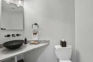 Half Bathroom with toilet and a textured wall off entry way