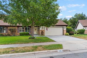 View of front of house with an attached garage, brick siding, driveway, and a front yard