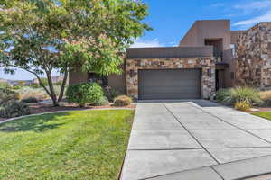 Contemporary home with an attached garage, stone siding, a front yard, concrete driveway, and stucco siding