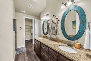 Full bathroom with double vanity, wood finished floors, and a walk in closet