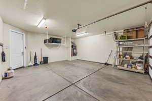 Garage featuring strapped water heater and baseboards