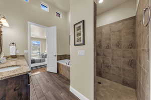 Full bathroom with wood finish floors, double vanity, a garden tub, tiled shower, and recessed lighting