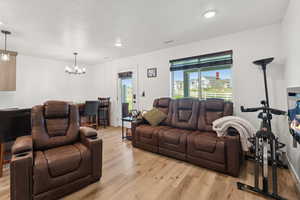 Living area with a chandelier, light wood finished floors, a textured ceiling, and recessed lighting