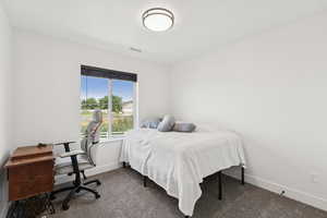Carpeted bedroom with an office area and a textured ceiling