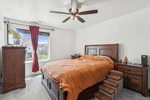 Bedroom with a textured ceiling, light carpet, and ceiling fan