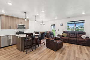 Living room with a textured ceiling, a chandelier, light wood-style floors, and recessed lighting