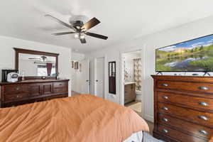 Bedroom featuring ensuite bathroom, a ceiling fan, light carpet, and a textured ceiling
