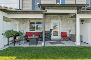 Doorway to property featuring a patio, a lawn, and stone siding