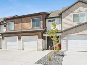 Craftsman-style house featuring board and batten siding, an attached garage, roof with shingles, driveway, and stone siding