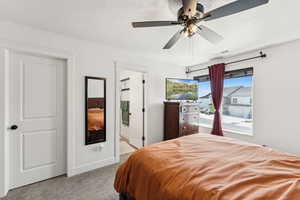 Carpeted bedroom with a textured ceiling, ceiling fan, and connected bathroom