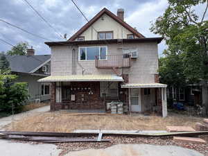 Back of house featuring a balcony, a porch, and a chimney