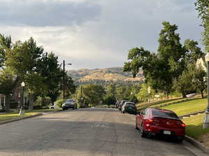 View of asphalt road featuring street lights, curbs, and a mountain view