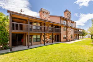 Rear view of property featuring a chimney, a lawn, and a patio