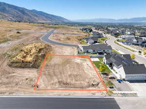 Aerial perspective of suburban area with a mountain backdrop and property parcel outlined