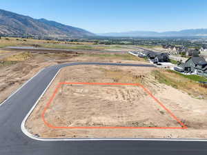 Aerial view of residential area with property parcel outlined and a mountain backdrop