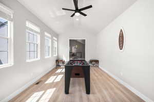 Rec room with lofted ceiling, light wood-style floors, and a ceiling fan