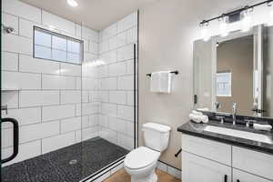 Full bath featuring a tile shower, vanity, wood finished floors, and recessed lighting