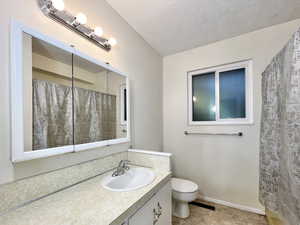Bathroom with vanity, a textured ceiling, curtained shower, and tile patterned flooring