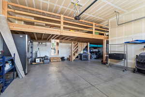 Garage with stainless steel refrigerator with ice dispenser and a garage door opener