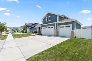 Craftsman-style home featuring driveway, a residential view, stone siding, and an attached garage