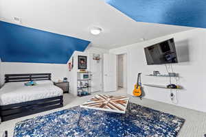 Carpeted bedroom featuring baseboards and vaulted ceiling