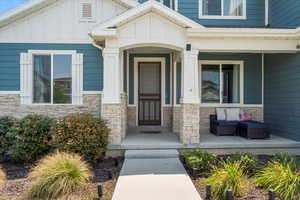 View of exterior entry featuring stone siding, a porch, and board and batten siding