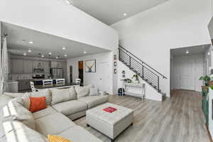 Living area featuring recessed lighting, light wood finished floors, stairway, and a towering ceiling