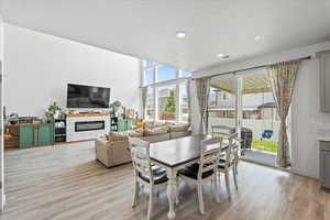 Dining room featuring light wood-type flooring, a glass covered fireplace, and recessed lighting