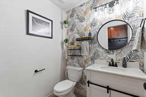 Half bath with wallpapered walls, vanity, and an accent wall