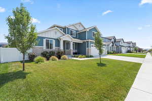 Craftsman-style house with concrete driveway, stone siding, a garage, board and batten siding, and a residential view