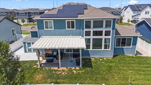 Back of house with roof with shingles, a fenced backyard, a patio, solar panels, and a residential view