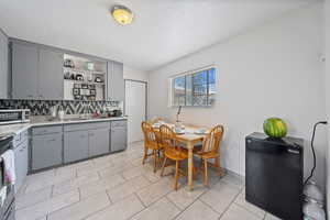 Kitchen with gray cabinetry, tasteful backsplash, appliances with stainless steel finishes, open shelves, and light countertops