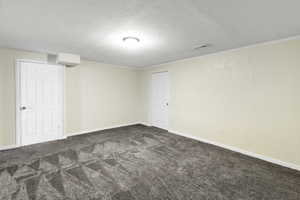 Finished below grade area featuring dark carpet, ornamental molding, and a textured ceiling