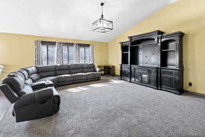 Carpeted living room with vaulted ceiling and a chandelier