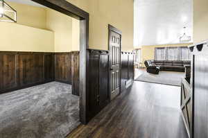 Hallway with wainscoting, wood finished floors, and wooden walls
