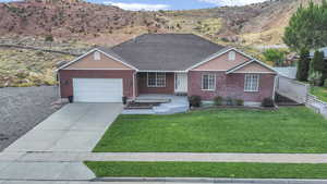 Ranch-style home featuring brick siding, driveway, an attached garage, and a mountain view