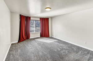 Empty room with a textured ceiling and carpet floors