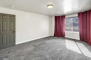 Unfurnished room featuring dark carpet and a textured ceiling