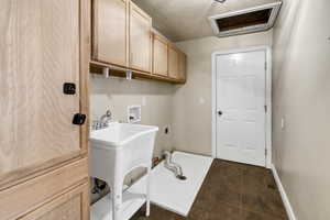 Washroom featuring hookup for an electric dryer, washer hookup, cabinet space, and dark tile patterned flooring