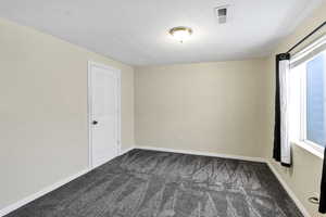 Spare room with dark carpet and baseboards