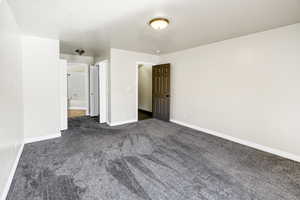 Unfurnished bedroom featuring dark colored carpet and baseboards