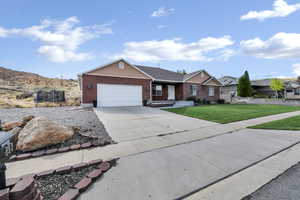 Ranch-style house featuring a trampoline, an attached garage, driveway, a front yard, and brick siding